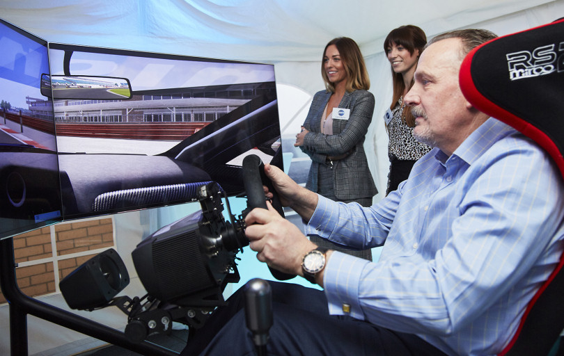 Pictured trying out the Formula 1 simulator is Philip Boot of Kloeckner Metals UK, watched by Sophie Norton (left) and Amy Nock of Pure Telecom