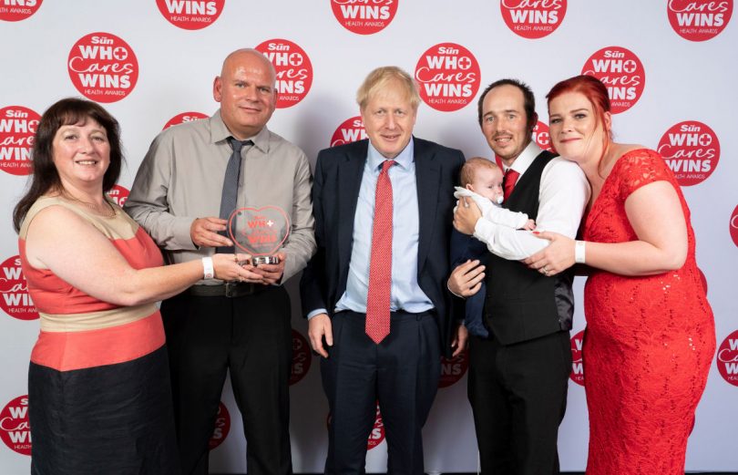 Prime Minister Boris Johnson stands alongside winners Nick Evans and Ruth Lowe, left, who were nominated by Sarah and Mike Clifford after saving their baby Logan. Photo: Dan Charity – The Sun