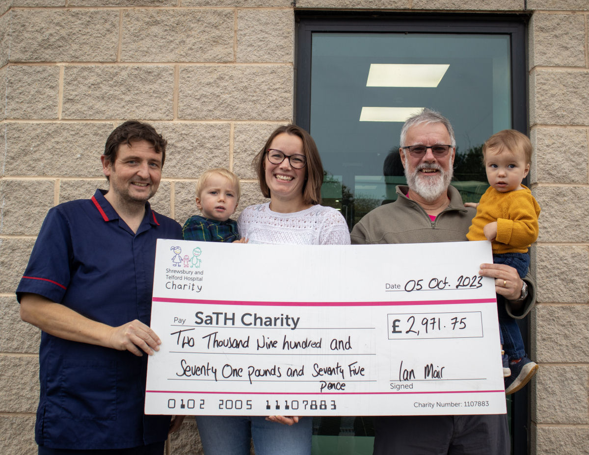 Ian Mair, his daughter Kathryn and his grandchildren present Peter Warren, Ward Manager, with a cheque