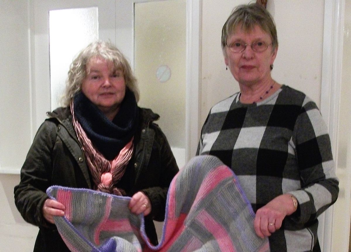 Nicola North and Rosemary Jacks with the knitted squares being transformed into a blanket